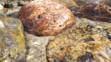 Renkli taşlarla dağ deresini kapatın. Düz taşlarla akan nehir. Farklı taşlardan akan kaynak suyu.