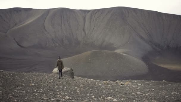 火山Hverfjallの上に岩の上に座っている女性と彼女は空に彼女の腕を上げる — ストック動画