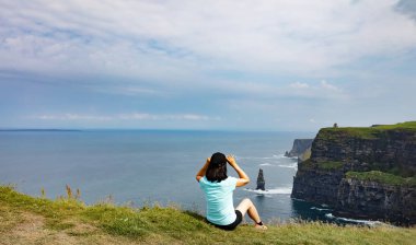 Okyanus ve kayalıklarla arayan kadın