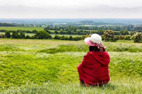 農場の牧草地を見ながら芝生で座っている女性 — ストック写真