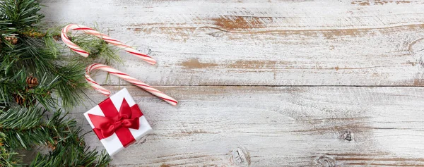 Raue Tannenzweige Mit Weihnachtsgeschenkschachtel Und Zuckerstangen Auf Rustikalen Weißen Holzbrettern — Stockfoto