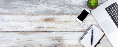 Dizüstü bilgisayar ve çalışma öğeleri ile beyaz rustik masa üstten görünüm 