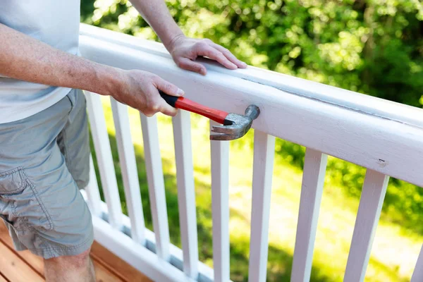 Close up of mature man hammering nail into white railing of outd — Stock Photo, Image