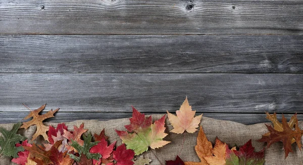 Foglie autunnali con tela di iuta su legno intemperie — Foto Stock