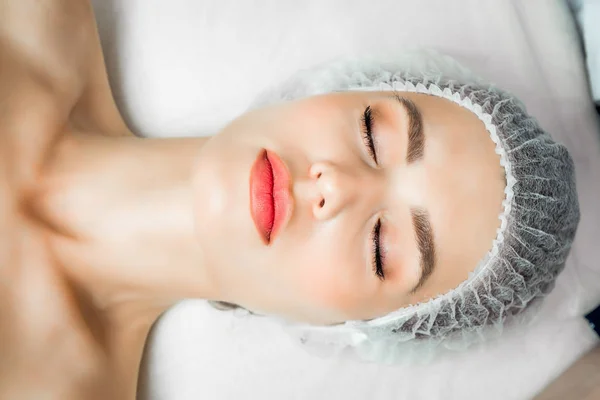 Le médecin cosmétologue effectue la procédure d'injections faciales rajeunissantes pour resserrer et lisser les rides sur la peau du visage d'une belle jeune femme dans un salon de beauté — Photo