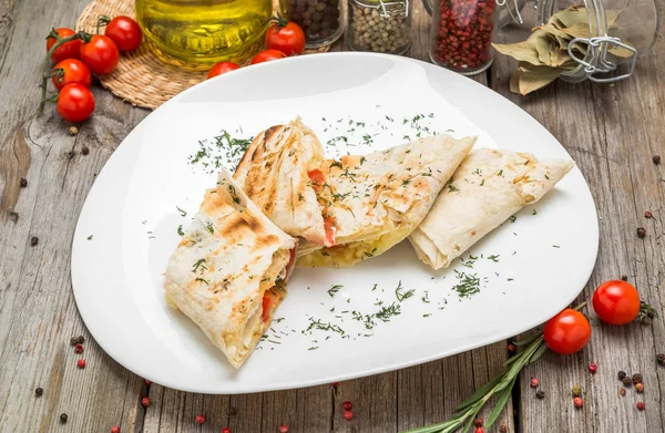 Shawarma sandwich or lavash with fresh vegetables and sauce on the gray plate decotated with cherry tomatoes, basil leaves on the gray table. — Stock Photo, Image