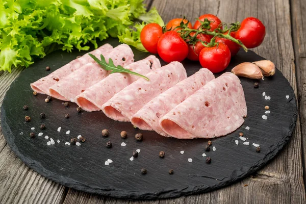 Cut sausage from ham on a wooden background — Stock Photo, Image