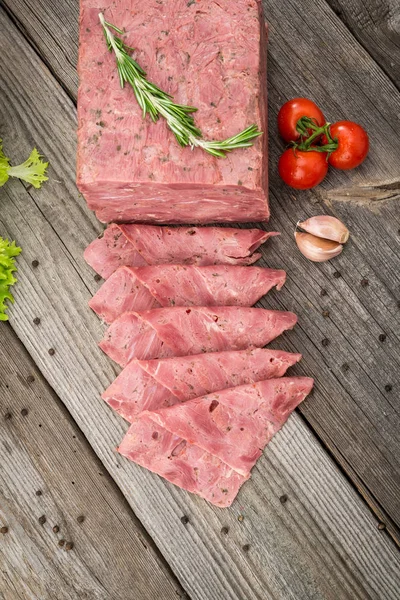 Cut sausage from ham on a wooden background