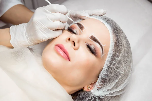 Permanent Makeup för ögonbryn. Närbild av vacker kvinna med tjocka ögonbryn i skönhetssalong. Kosmetolog gör ögonbryn tatuera för kvinnliga ansikte. Skönhet förfarande. — Stockfoto