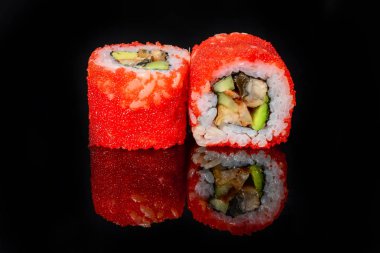 Geleneksel taze Japon suşisi siyah arka planda yuvarlanıyor.