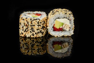Geleneksel taze Japon suşisi siyah arka planda yuvarlanıyor.