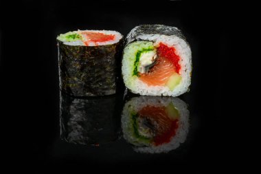 Geleneksel taze Japon suşisi siyah arka planda yuvarlanıyor.