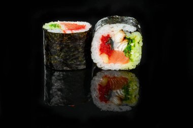 Geleneksel taze Japon suşisi siyah arka planda yuvarlanıyor.