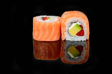 Geleneksel taze Japon suşisi siyah arka planda yuvarlanıyor.