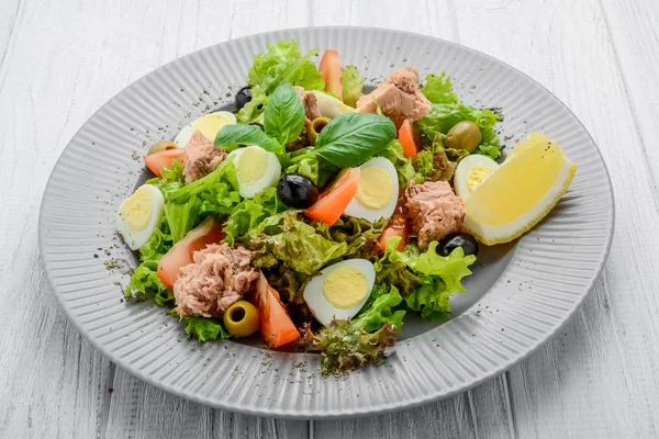 Tuna salad with tomatoes , olives , eggs and onion . — Stock Photo, Image