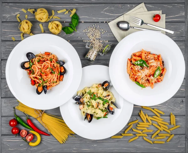 Almoço de estilo mediterrânico. Espaguete com mexilhões enlatados e molho de tomate. Em uma mesa de madeira, vista superior . — Fotografia de Stock