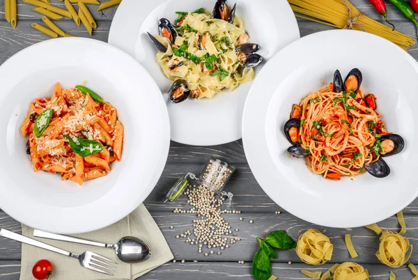 Almoço de estilo mediterrânico. Espaguete com mexilhões enlatados e molho de tomate. Em uma mesa de madeira, vista superior . — Fotografia de Stock