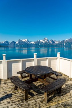 Piknik alanı dinlenme alanı ahşap masa dekorasyonu ve göl fiyort kıyısında Norveç bayrağı. Tatil ler gezide rahatlama. İskandinavya Avrupa.