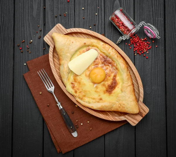 Hand mixing ingredients of adjarian khachapuri with fork in restaurant. Open bread pie with cheese and egg yolk. Yummy georgian cuisine. — Stock Photo, Image