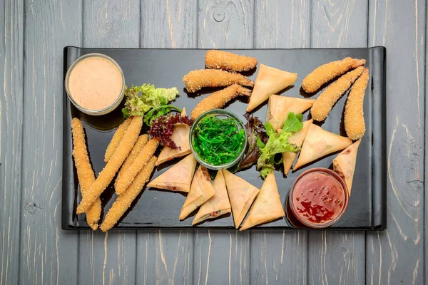 Farklı soslar ve salatalarla bir sürü lezzetli atıştırmalık. Ahşap arka planda