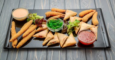 Farklı soslar ve salatalarla bir sürü lezzetli atıştırmalık. Ahşap arka planda