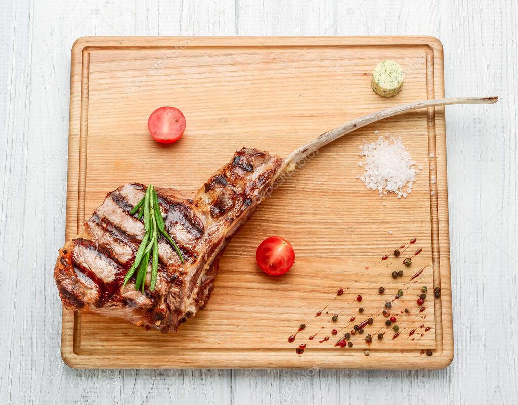 freshly grilled Tomahawk steaks on wooden cutting board