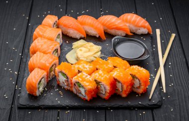 Sushi set nigiri ve suşi ruloları siyah taş levhada servis edilir, geleneksel Japon yemekleri.