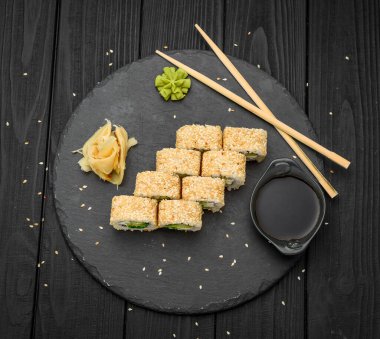 Sushi susamlı ve siyah arka planda krem peynirli.