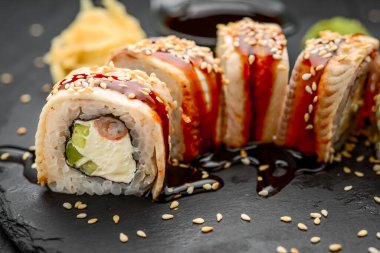 Siyah arka planda yılan balığı ve krem peynirli ejderha sarması.