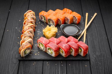 Sushi set nigiri ve suşi ruloları siyah taş levhada servis edilir, geleneksel Japon yemekleri.