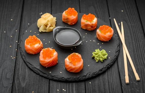 寿司卷 带有鲑鱼 奶油奶酪和鲑鱼鱼子酱的黑色底色 — 图库照片
