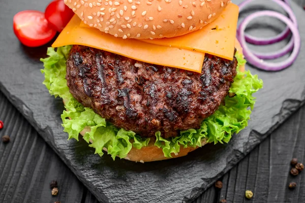 Hambúrguer caseiro com salada e queijo. Deitado em ardósia preta — Fotografia de Stock