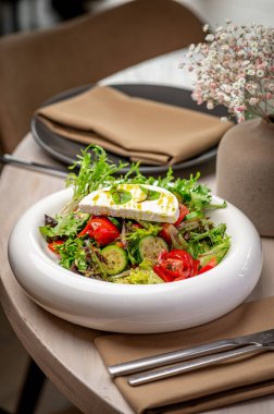 Moda bir kafede servis edilen lezzetli salata. Taze sebzeler ve sebzeler üzerinde krem peynir olan bir kasede güzelce düzenlenir. Hafif bir yemek için mükemmeldir..