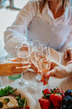 Arkadaşlar yemek ve içecekleri paylaşır. Özel bir anı kutluyoruz, arkadaşlar taze yiyecek ve meyvelerle dolu parlak bir masada köpüklü içkilerle kadeh kaldırıyoruz..