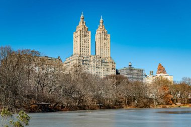 Central Park 'ın manzarası harika! Ziyaretçiler Central Park 'ta aydınlık mavi gökyüzüne karşı ikiz kulelere bakan açık bir günün tadını çıkarıyorlar..
