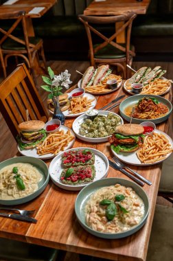Delicious spread of diverse dishes at dining table. A vibrant selection of various dishes is beautifully arranged on a wooden table, inviting food lovers to indulge.