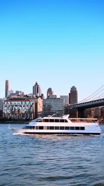New York, ABD, 1 Temmuz 2025: New York 'taki Manhattan Köprüsü' nün yanında yat gezisi. Beyaz bir yat Manhattan Köprüsü yakınlarındaki Doğu Nehri boyunca ilerliyor. Arka planda gökdelenler görünür..
