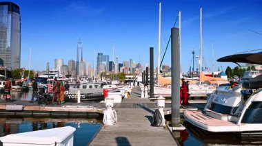 Jersey City, ABD, 1 Temmuz 2025, Manhattan Skyline manzaralı tekneler Jersey City marinasına yanaştı. Jersey City marinasına yanaşan teknelerin rıhtımında insanlar rıhtımda yürüyor ve arka planda Manhattan ufuk çizgisini net bir şekilde görüyor..