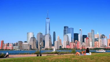 Hudson Nehri 'nin karşısındaki Manhattan siluetinde çimde dinlenen çift. Jersey City Parkı 'ndaki çimlerin üzerinde gevşeyen bir çift. Hudson Nehri' nin karşısındaki Manhattan silueti..