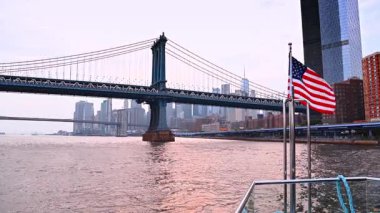 Nehirden Manhattan Köprüsü ve Brooklyn Köprüsü görünüyor. Manhattan Köprüsü 'nü ve Brooklyn Köprüsü' nü arka planda New York şehrinin siluetini gösteren bir tekneden görüntü..
