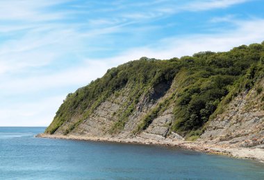 Boş kayalık deniz kıyısı ve açık bulutlar ile mavi gökyüzü