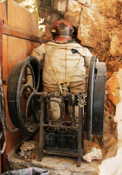 Vintage diving suit and hand diving pump used as tourist attractions in a souvenir shop in Symi town, Symi island, Greece