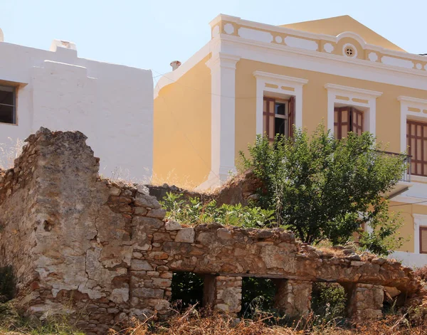 Arka planda renkli geleneksel bir ev olan harabe ev, Symi kasabası, Surmi Adası, Yunanistan