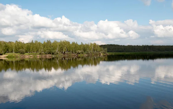 Orman gölü manzarası, bir gölün pürüzsüz yüzeyi, yansıyan bulutlar, parlayan bir orman gölü.