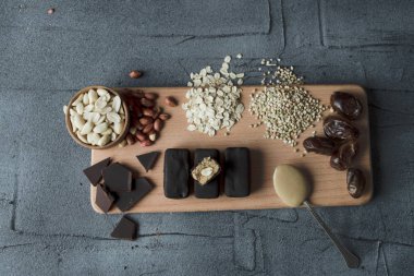 Ev yapımı snickers bar şekersiz. bir düzenlenen yarısı ile ahşap tahta üzerinde malzemelerle çiğ vegan tatlılar