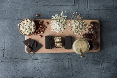 Ev yapımı snickers bar şekersiz. bir düzenlenen yarısı ile ahşap tahta üzerinde malzemelerle çiğ vegan tatlılar