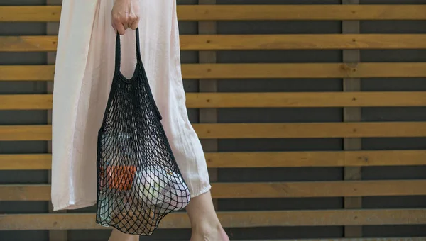 Mulher está segurando saco de malha com produtos — Fotografia de Stock