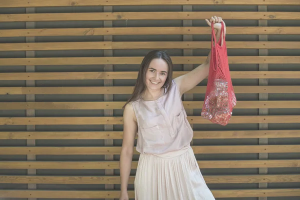 Kvinna håller mesh väska med produkter — Stockfoto