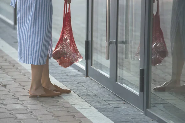 woman is holding mesh bag with products