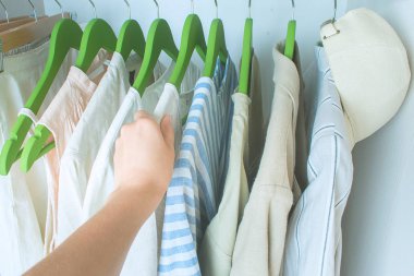 Yeşil askılarda keten giysiler olan bir gardırop.